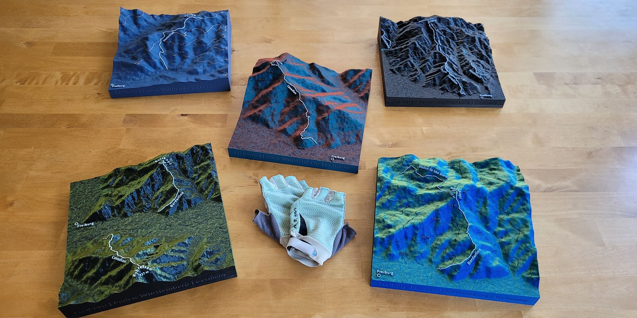 Mehrere verschiedenfarbige MTB-Trail Geländereliefs auf Holzuntergrund