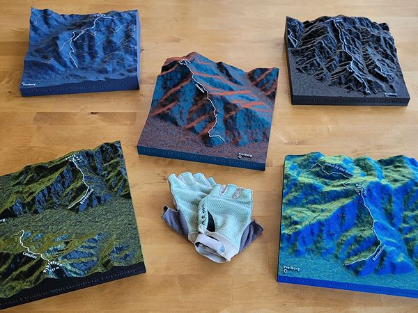 Mehrere verschiedenfarbige Geländereliefs von MTB Trails auf Holzuntergrund